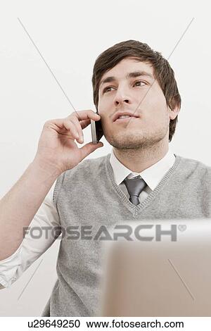 Businessman using laptop and cell phone View Large Photo Image Stock Image - Businessman using laptop and cell phone. Fotosearch
