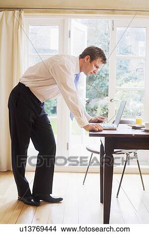 Picture - Businessman using laptop at breakfast. Fotosearch