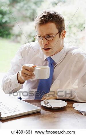Businessman using laptop at breakfast View Large Photo Image Stock Image - Businessman using laptop at breakfast. Fotosearch