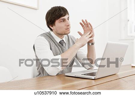 Stock Image - Businessman using laptop at desk. Fotosearch