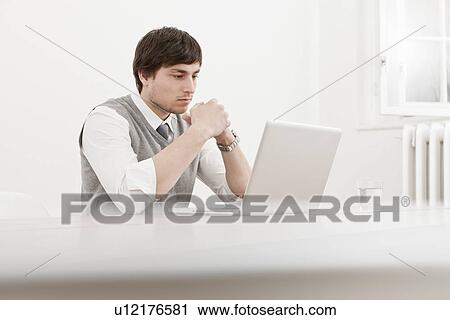 Stock Image - Businessman using laptop at desk. Fotosearch
