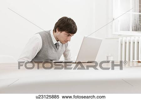 Stock Photography - Businessman using laptop at desk. Fotosearch