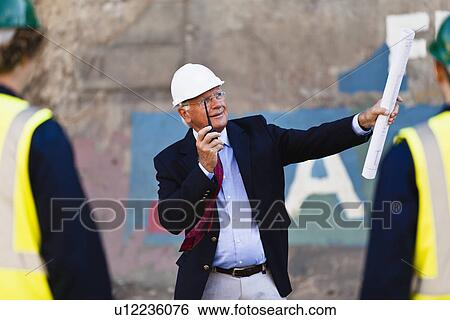 Businessman using walkie-talkie on site View Large Photo Image Stock Photograph - Businessman using walkie-talkie on site. Fotosearch