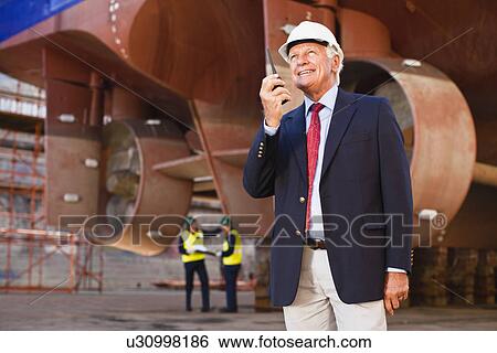 Businessman using walkie talkie on site View Large Photo Image Stock Photograph - Businessman using walkie talkie on site. Fotosearch