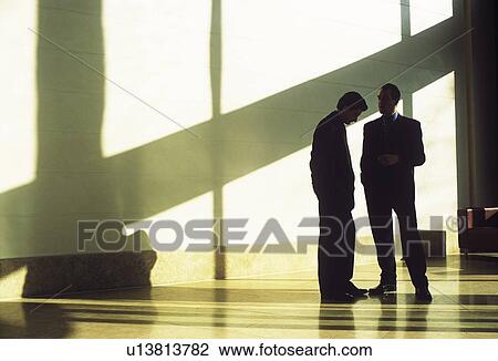 Businessmen talking in shadowed lobby View Large Photo Image Stock Image - Businessmen talking in shadowed lobby. Fotosearch