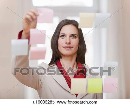 Stock Photography - Businesswoman hanging up sticky notes. Fotosearch