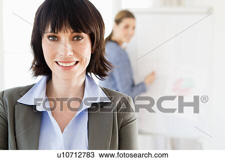 Stock Image - Businesswoman smiling in office. Fotosearch