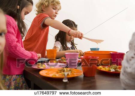 Children eating together at table View Large Photo Image Stock Photo - Children eating together at table. Fotosearch
