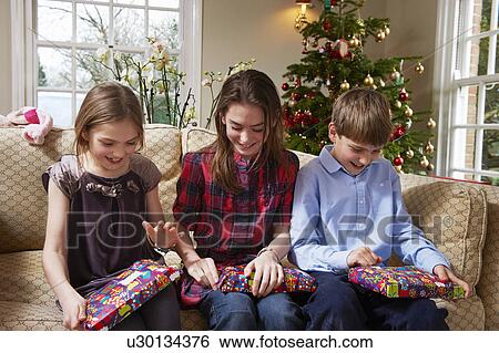 Stock Photograph - Children opening Christmas gifts. Fotosearch