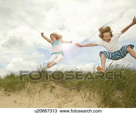 Stock Image - Children playing on grassy sand dune. Fotosearch