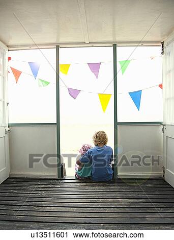 Stock Image - Children sitting in doorway together. Fotosearch