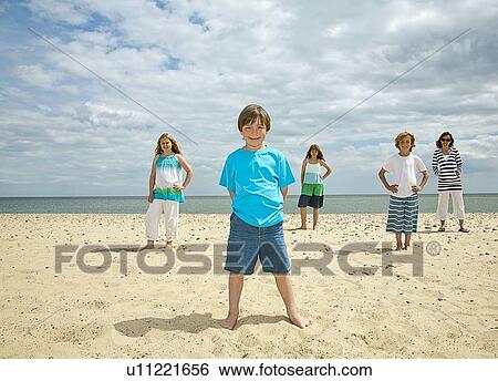 Stock Photograph - Children standing together on beach. Fotosearch