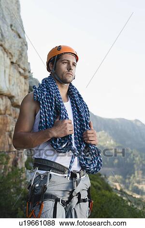 Stock Photo - Climber holding coiled rope on mountain. Fotosearch