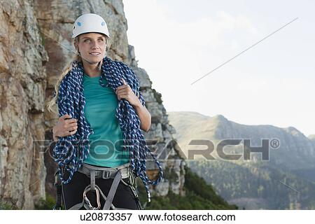 Stock Photo - Climber holding coiled rope on mountain. Fotosearch