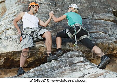 Stock Image - Climbers scaling steep rock face. Fotosearch