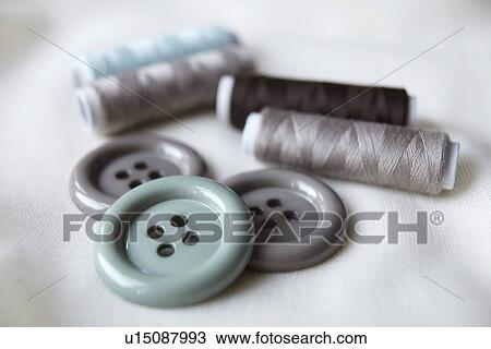Stock Image - Close up of buttons and spools of thread. Fotosearch