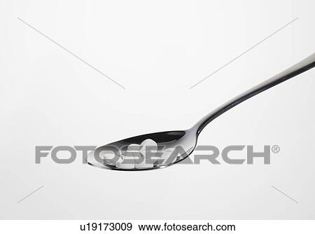 Stock Photo - Close up of spoonful of pills. Fotosearch