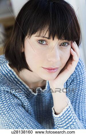 Stock Image - Close up of woman resting chin in hand. Fotosearch