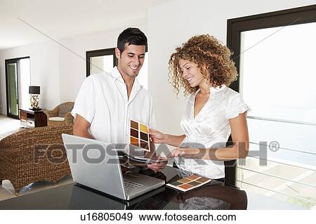 Stock Photo - Couple examining swatches in home. Fotosearch
