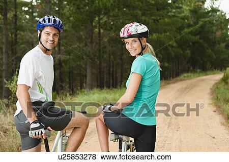 Couple mountain biking on dirt path View Large Photo Image Stock Photo - Couple mountain biking on dirt path. Fotosearch