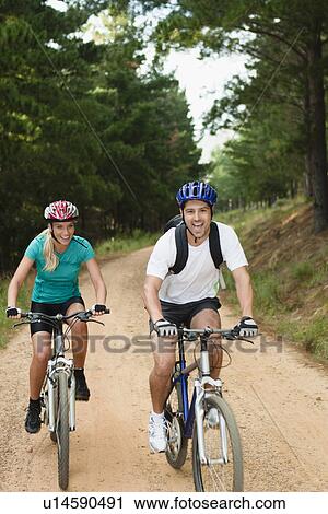 Couple mountain biking on dirt road View Large Photo Image Stock Image - Couple mountain biking on dirt road. Fotosearch