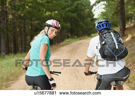 Couple mountain biking on dirt road View Large Photo Image Stock Image - Couple mountain biking on dirt road. Fotosearch