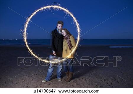 Couple playing with sparkler on beach View Large Photo Image Stock Photo - Couple playing with sparkler on beach. Fotosearch