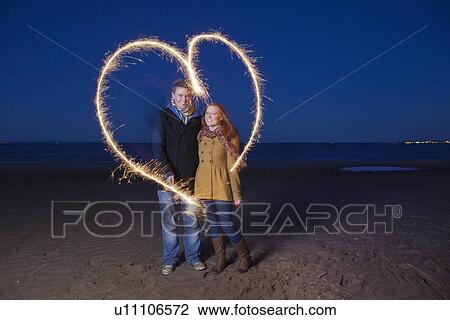 Couple playing with sparklers on beach View Large Photo Image Stock Image - Couple playing with sparklers on beach. Fotosearch