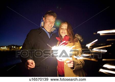 Couple playing with sparklers on beach View Large Photo Image Stock Photo - Couple playing with sparklers on beach. Fotosearch