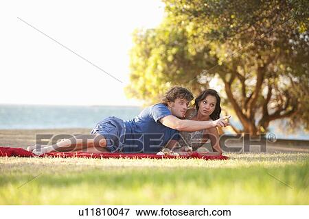 Couple relaxing on picnic blanket View Large Photo Image Stock Photo - Couple relaxing on picnic blanket. Fotosearch