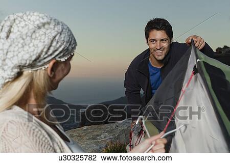 Couple setting up tent on hillside View Large Photo Image Stock Image - Couple setting up tent on hillside. Fotosearch