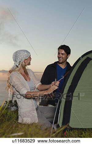 Couple setting up tent on hillside View Large Photo Image Stock Photo - Couple setting up tent on hillside. Fotosearch