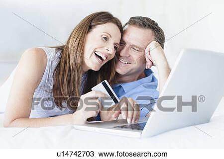 Couple shopping online on bed View Large Photo Image Stock Image - Couple shopping online on bed. Fotosearch