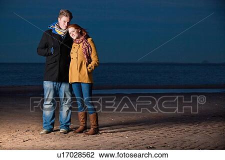 Stock Image - Couple standing together on beach. Fotosearch