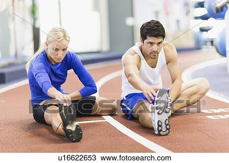 Couple stretching on indoor track in gym View Large Photo Image Stock Image - Couple stretching on indoor track in gym. Fotosearch