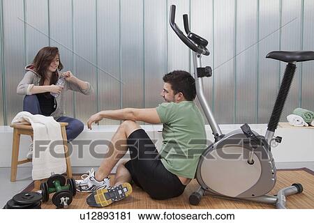 Stock Image - Couple talking in home gym. Fotosearch