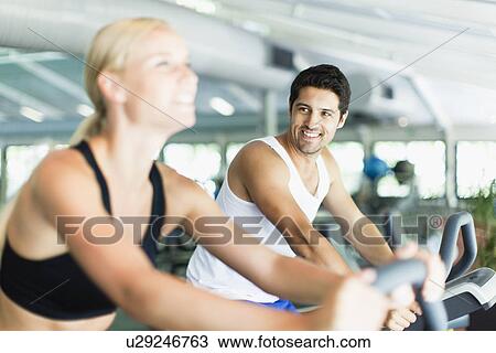 Couple using exercise machines in gym View Large Photo Image Stock Image - Couple using exercise machines in gym. Fotosearch
