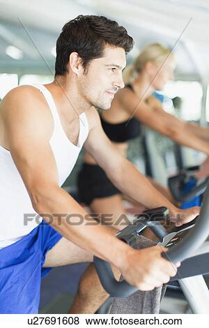 Couple using exercise machines in gym View Large Photo Image Stock Photo - Couple using exercise machines in gym. Fotosearch