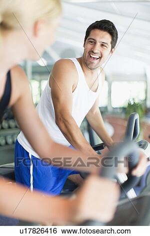 Couple using exercise machines in gym View Large Photo Image Stock Photograph - Couple using exercise machines in gym. Fotosearch