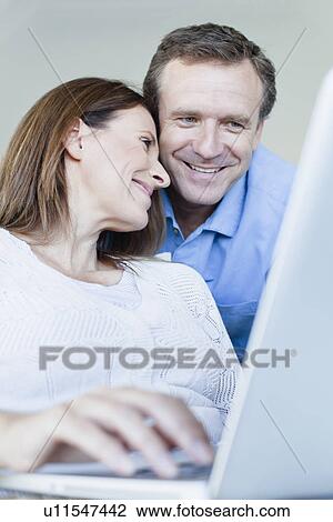Couple using laptop in armchair View Large Photo Image Stock Image - Couple using laptop in armchair. Fotosearch
