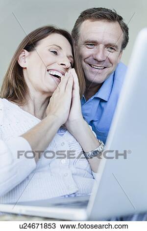 Couple using laptop in armchair View Large Photo Image Stock Image - Couple using laptop in armchair. Fotosearch