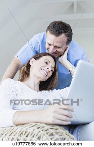 Stock Photograph - Couple using laptop in armchair. Fotosearch
