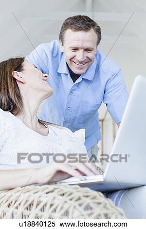Stock Photography - Couple using laptop in armchair. Fotosearch