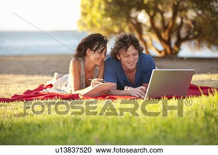 Couple using laptop on picnic blanket View Large Photo Image Stock Image - Couple using laptop on picnic blanket. Fotosearch