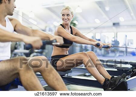 Couple using rowing machines in gym View Large Photo Image Stock Photo - Couple using rowing machines in gym. Fotosearch