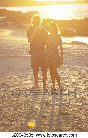 Stock Photography - Couple walking barefoot on beach. Fotosearch
