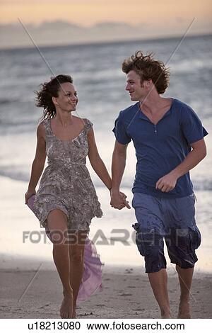 Stock Image - Couple walking together on beach. Fotosearch