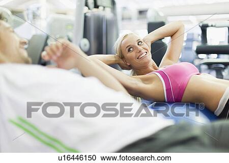 Stock Image - Couple working out together in gym. Fotosearch