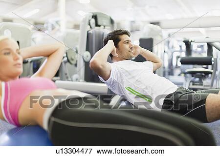 Stock Photo - Couple working out together in gym. Fotosearch