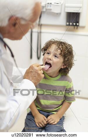 Stock Image - Doctor examining boy in office. Fotosearch